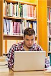 Handsome focused student using laptop in library