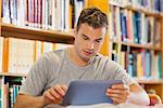Attractive casual student using tablet in library