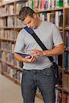 Handsome serious student looking at tablet in library