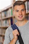 Handsome smiling student looking at camera in library