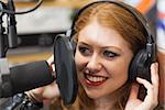 Happy beautiful singer recording a song in studio at college