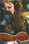 Content beautiful singer recording and playing guitar in studio at college