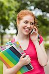 Gorgeous cheerful student holding notebooks phoning on campus at college