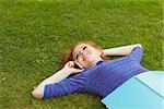 Gorgeous smiling student lying on grass phoning on campus at college