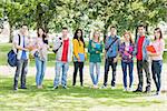 Group portrait of young college students with bags and books standing in the park