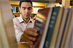 Close up of a serious mature student selecting book from shelf in the library