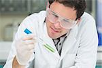 Close up of a male scientist analyzing green solution in test tube at the laboratory