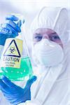 Close up of a scientist in protective suit with hazardous blue chemical in flask at the laboratory