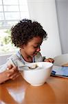 Boy eating breakfast and using digital tablet