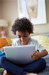 Child sitting on bed using digital tablet