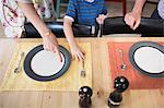 Son setting the table, mother pointing