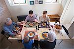 Three generation family holding hands at dinner table