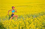 Young woman running in oil seed rape field