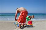 Two young brothers building sandcastles on beach