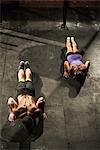 Two young adults doing push ups in gym