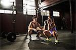 Young woman and personal trainer working out in gym