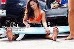 Woman sitting with surfboard, Hermosa Beach, California, USA