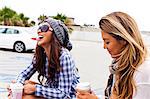 Female friends sitting in car lot, Hermosa Beach, California, USA