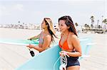 Female friends carrying surf boards, Hermosa Beach, California, USA