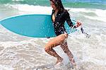 Woman running through waves, Hermosa Beach, California, USA