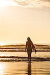 Young woman with surfboard at sunset, La Jolla, San Diego, California, USA