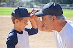 Boy and grandfather in baseball caps, face to face