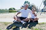 Grandfather and grandson sitting on sports field