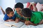 Father and sons reading on bed
