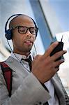 Young man wearing headphones and glasses using mp3 player