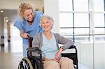 Nurse and aging patient smiling in hospital corridor