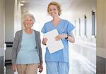 Portrait of smiling nurse and senior patient in hospital corridor