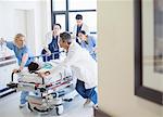 Doctors and nurses rushing patient on stretcher down hospital corridor