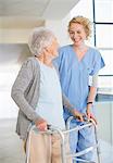 Senior patient with walker smiling at nurse in hospital corridor