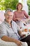 Senior man using digital tablet in armchair on patio