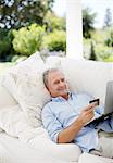 Senior man shopping online on patio sofa