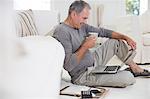 Senior man using laptop on living room floor