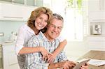 Portrait of smiling senior couple with digital tablet in kitchen