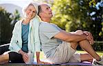 Senior couple sitting on yoga mat in park