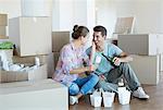 Couple drinking champagne and eating Chinese food on floor in new house