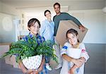 Portrait of smiling family holding belongings in new house