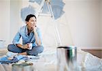 Woman relaxing with coffee among painting supplies