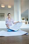 Woman with blueprints on floor in new house