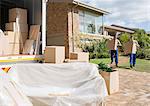 Movers carrying cardboard boxes from house to moving van