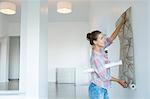 Woman hanging wallpaper in new house