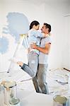 Couple hugging among paint supplies