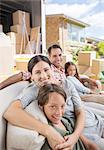 Family sitting on sofa near moving van in driveway