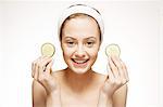 Smiling woman holding cucumber slices