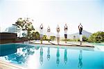 People practicing yoga at poolside