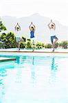 Men and woman practicing yoga at poolside