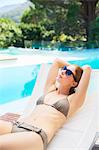 Woman relaxing on lounge chair at poolside